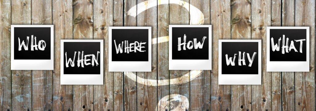 Sanat Who, When, Where, How,
Why ja What kehyksissä puisella pinnalla.