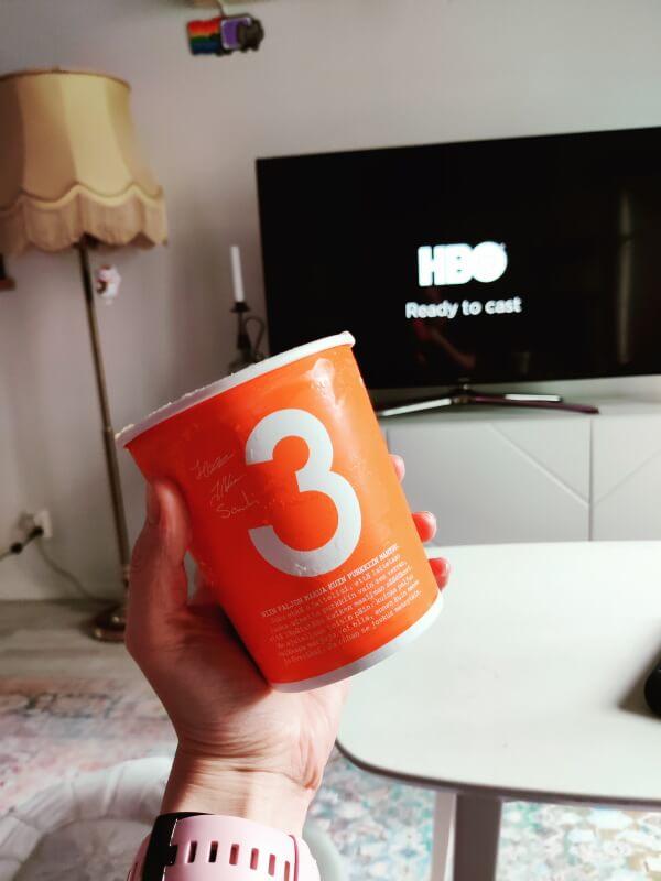 Kuvassa puolen litran jäätelöpurkki ja tv-ruutu, jossa näkyy HBO:n logo.